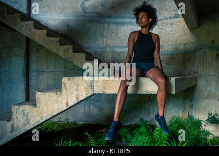 Il Melanesian pacific islander atleta ragazza con forti braccia dopo la seduta di allenamento a scala in edificio abbandonato Foto Stock