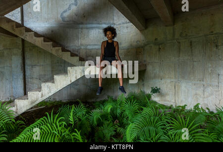 Il Melanesian pacific islander atleta ragazza con forti braccia dopo la seduta di allenamento a scala in edificio abbandonato Foto Stock