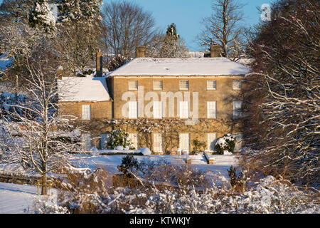 Bourton sulla collina casa padronale nella neve a sunrise in dicembre. Bourton sulla collina, Cotswolds, Gloucestershire, Inghilterra. Foto Stock