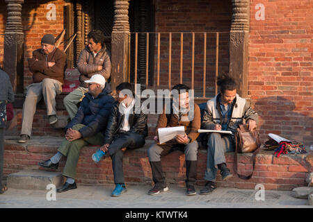 Gruppo di uomini Nepalese seduti al sole a Durbar Square, Kathmandu, Nepal Foto Stock