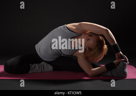 Giovane donna a praticare yoga, Janu Sirsasana / giravano testa a ginocchio Foto Stock