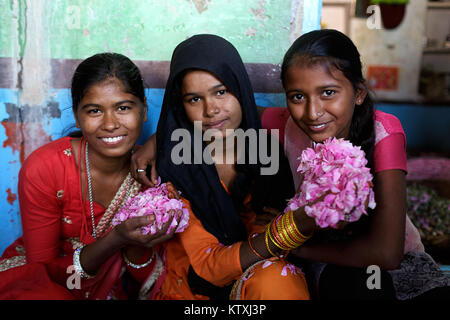 Tre sorridenti giovani indiani ragazze in abiti tradizionali azienda petali di fiori nella loro casa di villaggio nei pressi di Pushkar, Rajasthan, India. Foto Stock