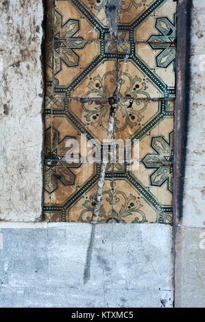 Vecchio, danneggiato, azulejo portoghese le piastrelle di ceramica con un disegno floreale che ornano le pareti esterne di un edificio a Lisbona, Portogallo. Foto Stock
