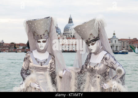 Il Carnevale di Venezia 2017, Veneto, Italia due donne in argento che pongono a laguna con la Basilica di Santa Maria della Salute dietro Foto Stock