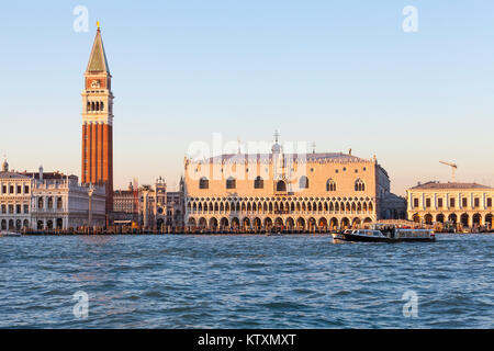 Il Palazzo dei Dogi, il campanile e la Torre dell Orologio, San Marco e Piazza San Marco al tramonto, Venezia, Italia dalla laguna con un vaporetto Foto Stock