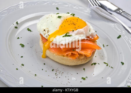 Soft Uovo affogato su muffin tostato con salmone affumicato su piastra bianca intaglio su sfondo bianco Foto Stock