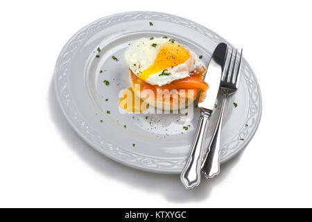 Soft Uovo affogato su muffin tostato con salmone affumicato su piastra bianca intaglio su sfondo bianco Foto Stock