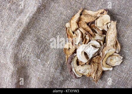 Fungo essiccato su un letto di sacco. Vista superiore funghi porcini secchi. Foto Stock