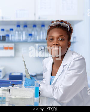 African-scienziato americano o studente laureato in camice e guanti protettivi sorrisi a fotocamera Foto Stock