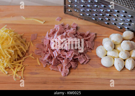 Il formaggio grattugiato e il prosciutto tritato, palline di mozzarella e grattugia su sfondo di legno Foto Stock