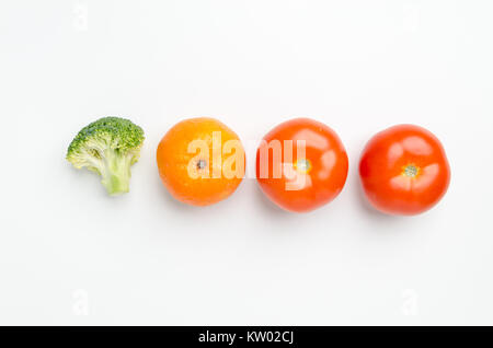 Fila di verdure fresche: pezzo di broccoli, Mandarine clementine/e due pomodori, isolato su sfondo bianco. Foto Stock