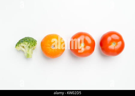 Fila di verdure fresche: pezzo di broccoli, Mandarine clementine/e due pomodori, isolato su sfondo bianco. Foto Stock