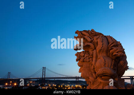 Vista del 25 aprile Bridge (Ponte 25 de Abril) a Lisbona, Portogallo. Una scultura si erge nel far risaltare al Miradouro do Largo das Necessidades. Foto Stock