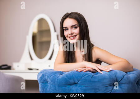 Home lifestyle donna rilassante sulla sedia sul soggiorno. Lady felici sdraiati su comodi cuscini prendendo un pisolino per il benessere e la salute. Foto Stock