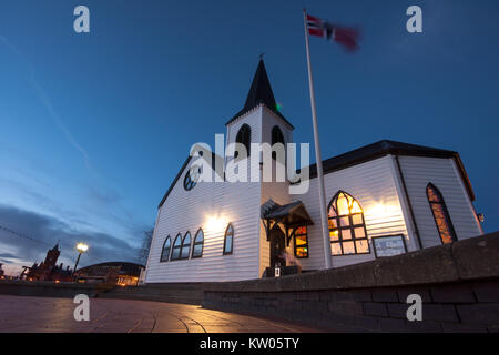 Cardiff Wales, Regno Unito - 17 Marzo 2013: Il legno bianco Chiesa Norvegese è illuminata di notte sulla banchina della Baia di Cardiff in Galles, con il norvegese Foto Stock