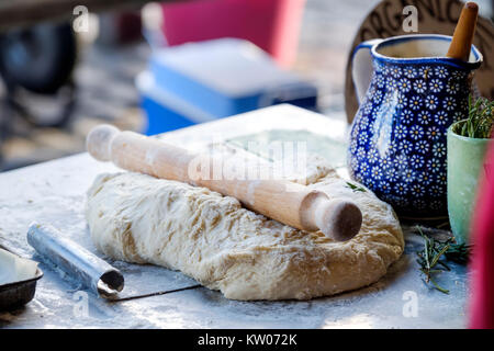 Preparate di fresco impasto per la realizzazione di focaccia italiana in attesa di essere tagliato in porzioni su un pane biologico in stallo al di fuori di un mercato alimentare Foto Stock