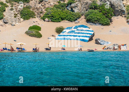 Tsambika spiaggia con sabbia dorata con grande bandiera greca dipinta sulla roccia (RHODES, Grecia) Foto Stock