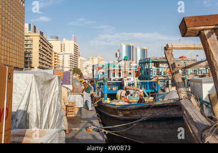 Operai locali di carico di lavoro spedizioni cargo dal quayside / procedure Dockside Wizard in un tradizionale vecchio dhow ormeggiati in Deira, Dubai Creek, Dubai, UAE Foto Stock