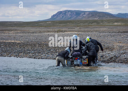 KEL-SUU, Kirghizistan - 13 agosto: gruppo di motociclisti spingendo la moto per attraversare il fiume su off road drive in Tian Shan montagne, Kirghizistan. Agosto Foto Stock