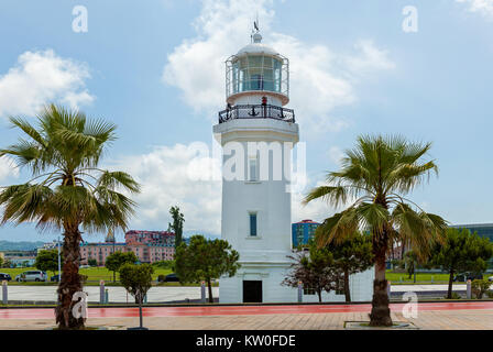 Faro contro lo sfondo della città. Un faro bianco contro una luce blu del cielo nella luce del giorno. Foto Stock