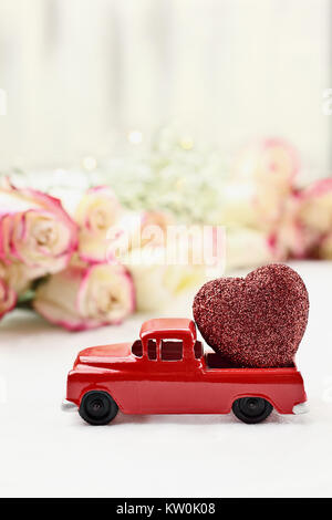 Anni Cinquanta antique vintage red carrello trasporta un glittery cuore rosso passato un rotolo di bella gambo lungo rose. Estrema profondità di campo con il selettivo Foto Stock