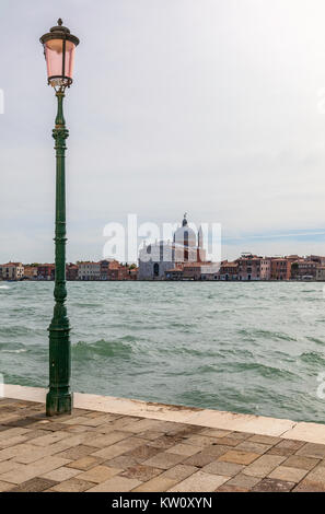 Vista sul Canale del Giudecca alla secentesca chiesa del Santissimo Redentore Venezia nel tardo pomeriggio di sole e con un alto standard di lampada in primo piano Foto Stock