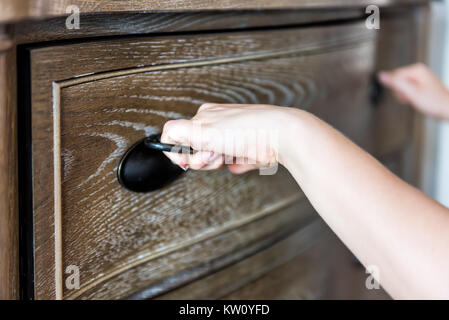 Primo piano della cassa di legno cassetto in camera da letto con luce naturale in casa di staging, casa appartamento il modello e la donna con le mani in mano la sua apertura Foto Stock