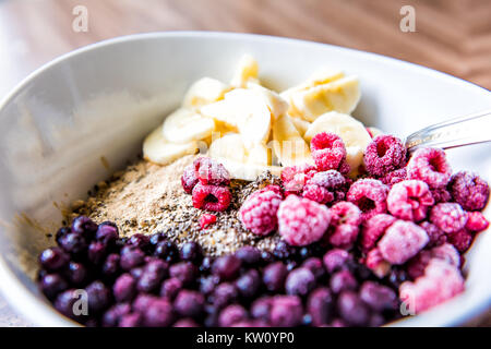 Mirtilli surgelati, lamponi, banana, maca e chia semi condimenti su porridge di avena Foto Stock