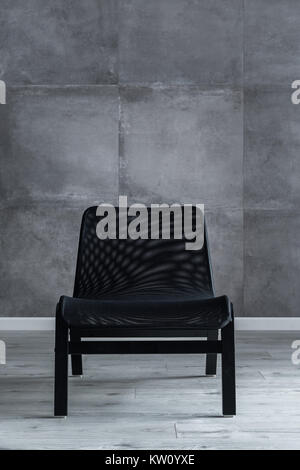 Designer nero sedia netto sul cemento grigio Sfondo a parete Foto Stock
