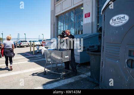 Nel bacino di Cina quartiere di San Francisco, un senzatetto carichi di rifiuti da un cassonetto in un carrello, 2016. Foto Stock