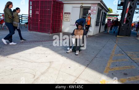 Nel bacino di Cina quartiere di San Francisco, un senzatetto detiene una lettura del segno "Marina" Vet e chiede di cambiare da passanti, San Francisco, California, 2016. Foto Stock