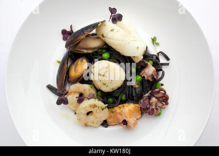 Pasta di colore nero con frutti di mare sulla piastra bianca. Cozze e gamberi. Vista superiore Foto Stock