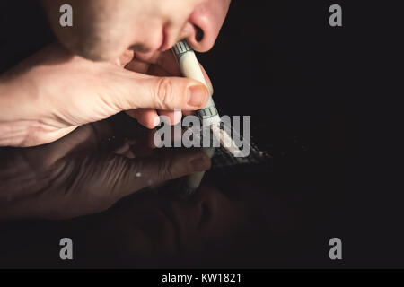 Junkie sbuffare è la cocaina in polvere con la banconota arrotolata. Concetto di stupefacenti. Foto Stock