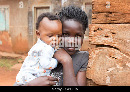 Lugazi, Uganda. 09 giugno 2017. Una giovane ragazza africana tenendo il suo bambino la sorella o il suo bambino in braccio. Foto Stock