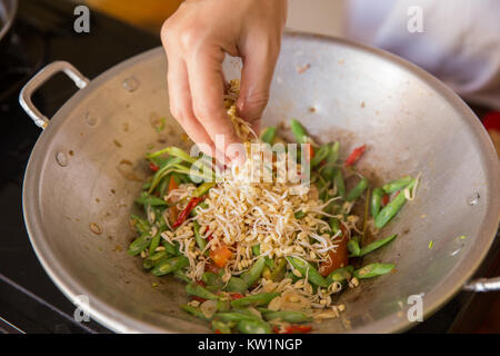 Aggiunta di germogliare in stir fry di fagioli e verdure Foto Stock