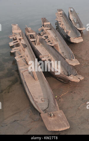 Vintage in legno canoe stand in una fila sul brown riverbank. Foto Stock