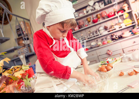 Carino il bambino in cucina mentre la miscelazione l'impasto per dolci fatti in casa il cibo Foto Stock