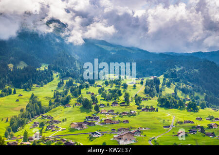 Bellissima vista idilliaco paesaggio di montagna delle Alpi con vecchi chalets in freschi prati verdi, Grindelwald, Alpi Bernesi, Svizzera Foto Stock