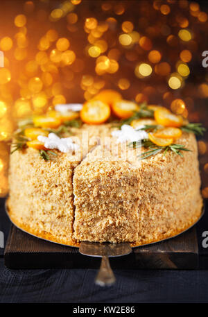 Natale torta di miele di rosmarino e le arance in tavola nera e oro sfondo bokeh di fondo. Foto Stock