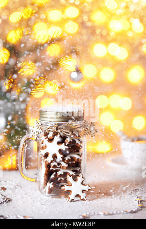 Gingerbread stelle nel vasetto di vetro sul tavolo bianco al golden bokeh sfondo con neve intorno a. Foto Stock