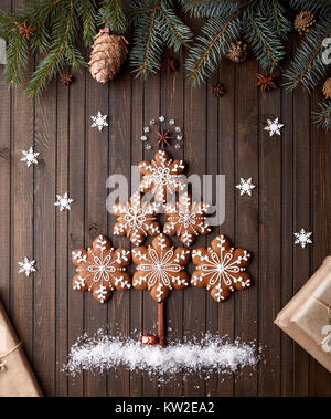 Albero di Natale da gingerbread stelle con neve intorno sul rustico sfondo marrone Foto Stock