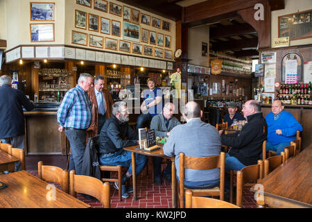 I clienti a guardare gli anziani giocatori di carte le carte da gioco in Café De Presse, pub belga nella città di Geraardsbergen / Grammont, Fiandre Orientali, Belgio Foto Stock