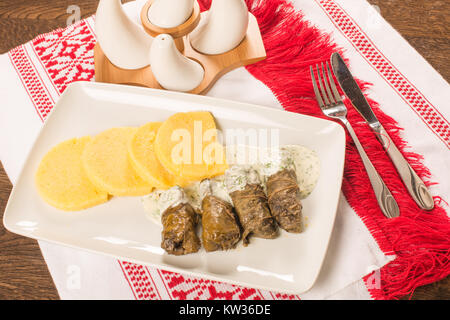 Foglie di uva rotoli con panna acida salsa su uno sfondo tradizionale Foto Stock