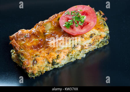 Close up di lasagne al salmone su una piastra nera Foto Stock