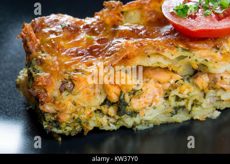 Close up di lasagne al salmone su una piastra nera Foto Stock