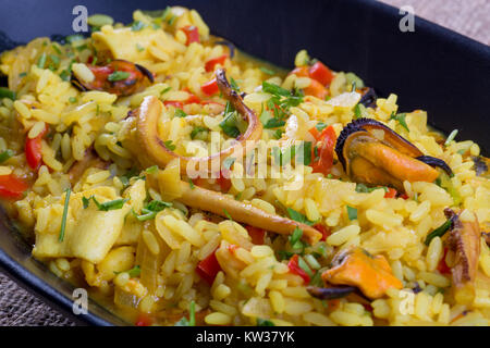 Chiusura del risotto ai frutti di mare su una piastra nera Foto Stock