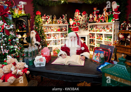 Stati Uniti Virginia VA Williamsburg Santa Claus Babbo Natale Saint Nicolas seduto nella sua sedia nel suo laboratorio facendo una lista nel suo libro Foto Stock