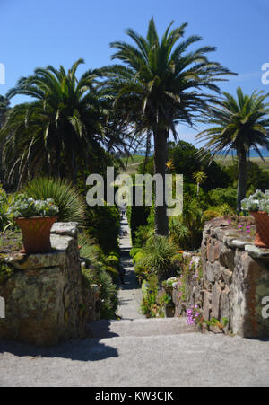 La gente sul faro passeggiata che conduce alla scultura di tre Tresco bambini che giocano in Abbey Gardens, Tresco, isole Scilly, Cornwall, Regno Unito Foto Stock