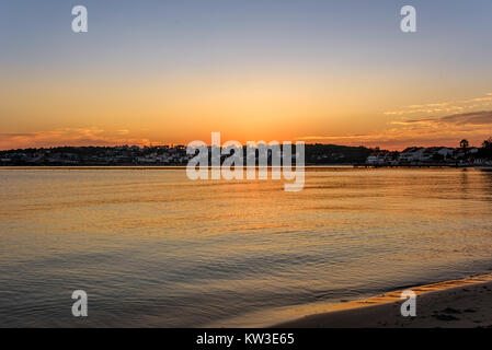 Sunrise con cieli chiari su una spiaggia e mare calmo Foto Stock