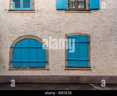 Blu di windows su pareti di giallo pallido di una piccola città Foto Stock